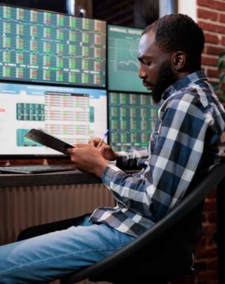investment-company-employee-doing-financial-analysis-having-clipboard-with-capital-documentation-forex-stock-market-trader-analyzing-real-time-trend-charts-while-sitting-multi-monitor-workstation (1)
